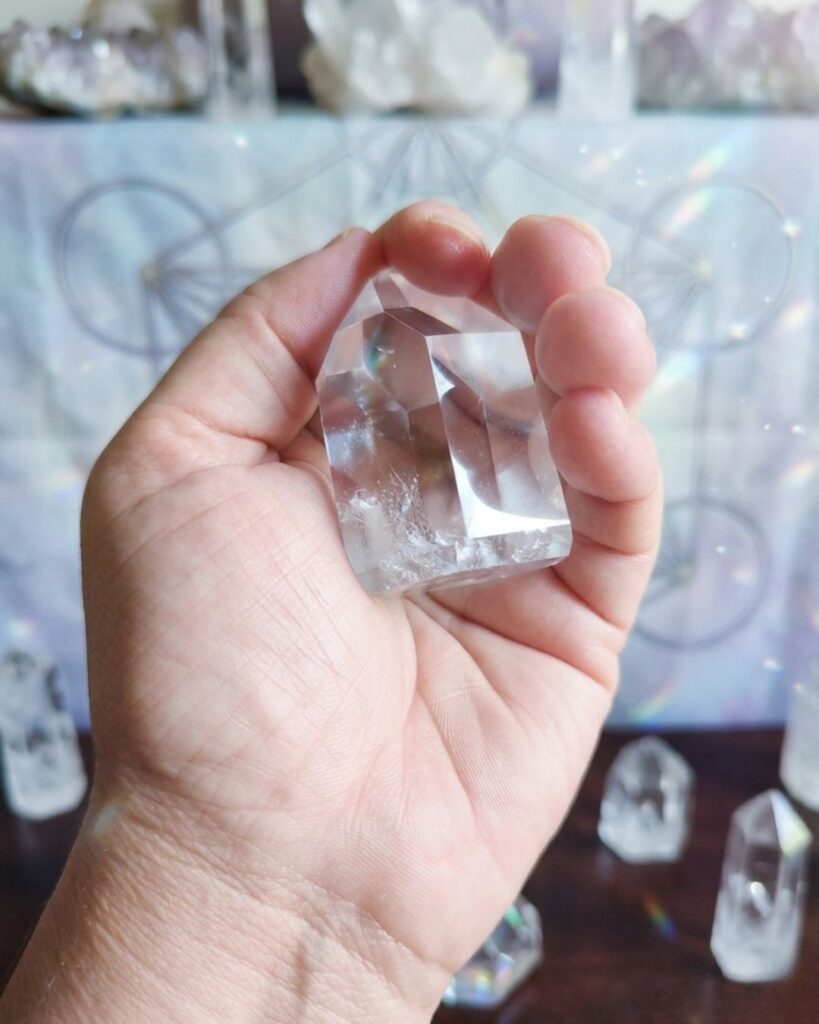 Uma foto de mãos femininas em posição de acolhimento (concha), segurando um cristal, com uma luz sutil saindo dele.